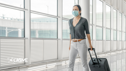 Woman walking through an airport, wearing a mask